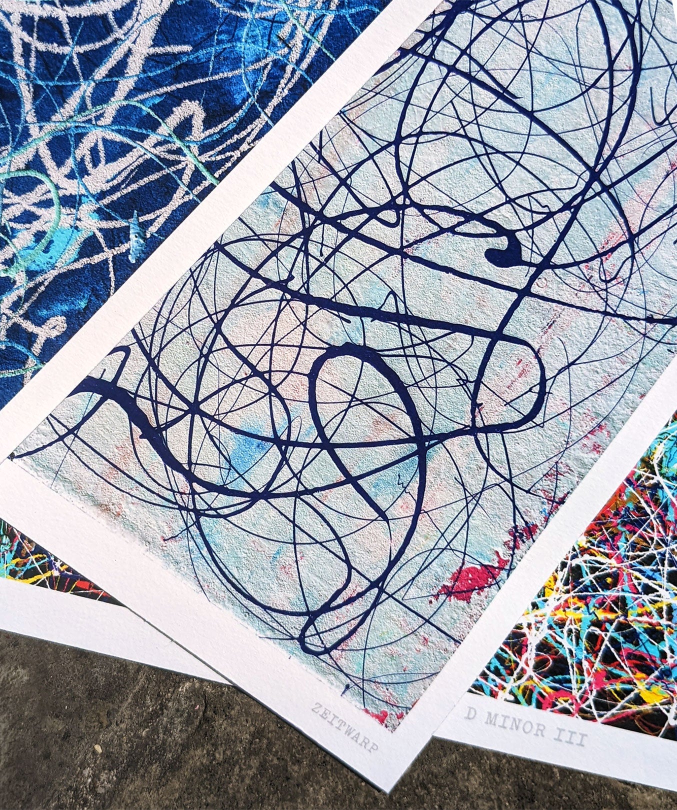 Three abstract music themed art giclée prints spread on a stone floor
