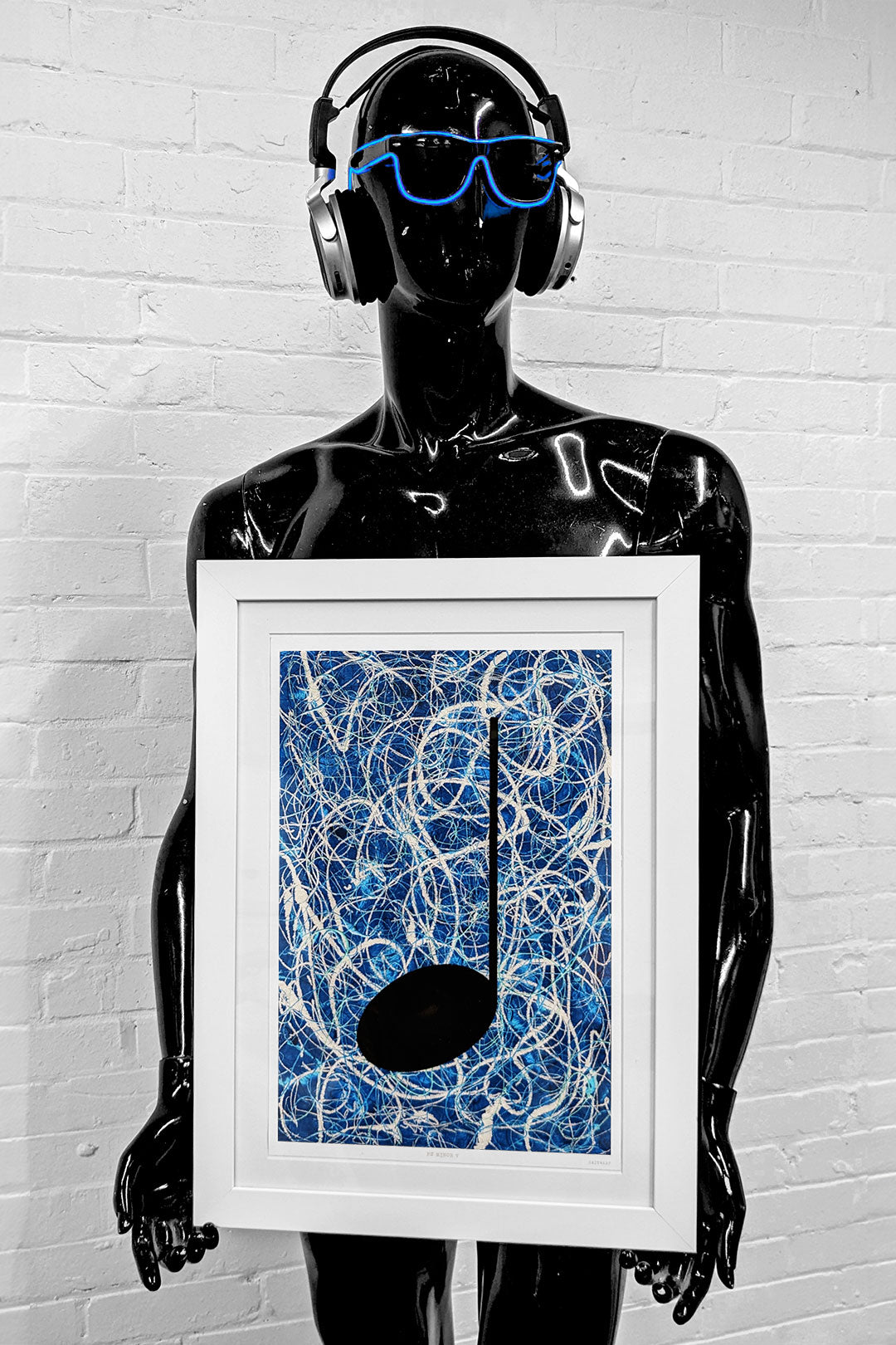 Blue framed music art giclée print held by a black mannequin with blue sunglasses and headphones