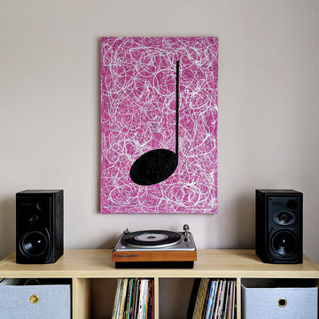 Pink, silver and black music themed street art painting hanging on a wall above a record turntable on a table