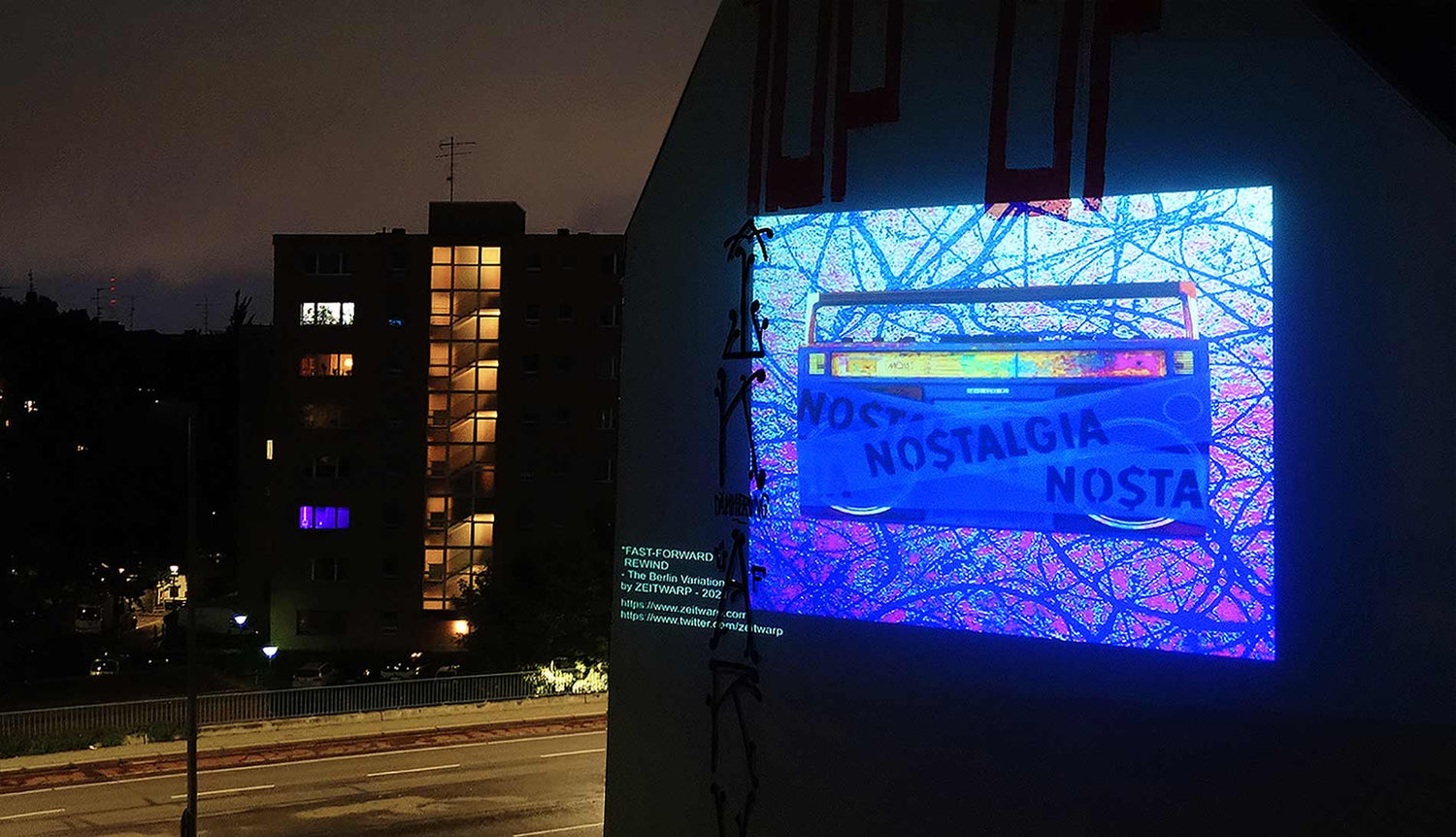 A digital art projection of the artwork 'FAST FORWARD / REWIND' on a building in Berlin at night