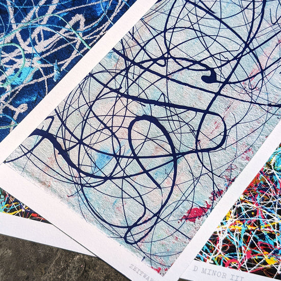 Three abstract music themed art giclée prints spread on a stone floor