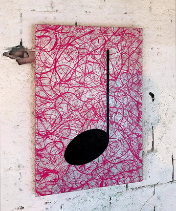 Pink, silver and black music themed street art painting hanging on a wall in an industrial setting